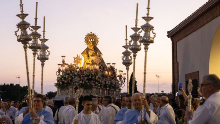 Procesión al atardecer con la imagen de Nuestra Señora de la Consolación rodeada de fieles y candelabros en las fiestas patronales.